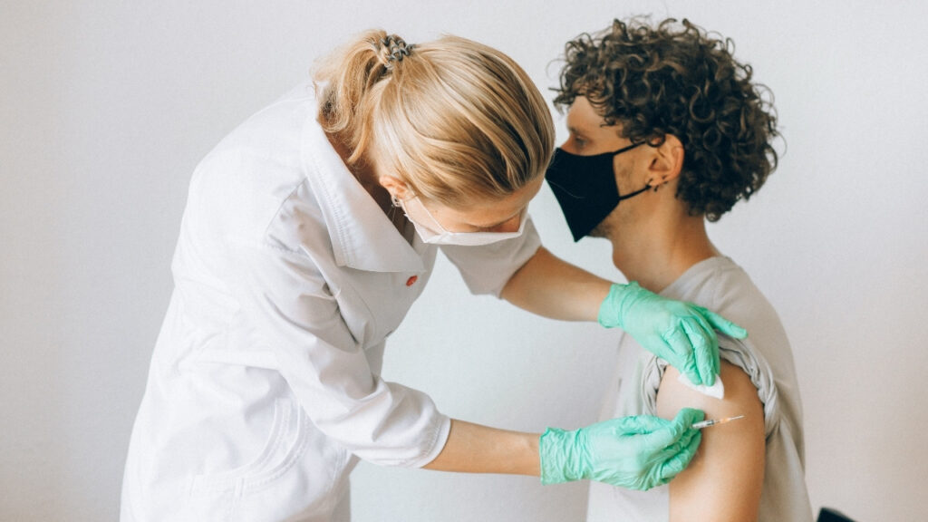 Doctor administering a vaccine to a patient’s upper arm.