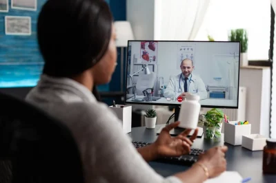 a person at a desk in a telehealth session with an online doctor.